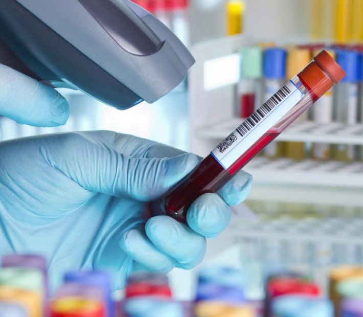 A hand holds a test tube while scanning it with a handheld scanner